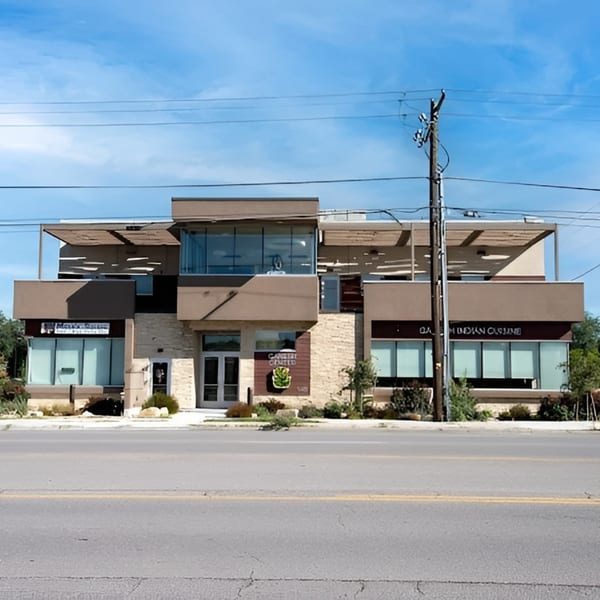Exterior of a modern, multi-story building housing "Garden Grille" and "Indian Cuisine" restaurants.