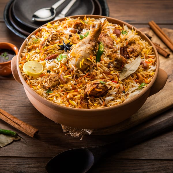 Chicken biryani in a clay pot, garnished with lemon, star anise, and bay leaf.